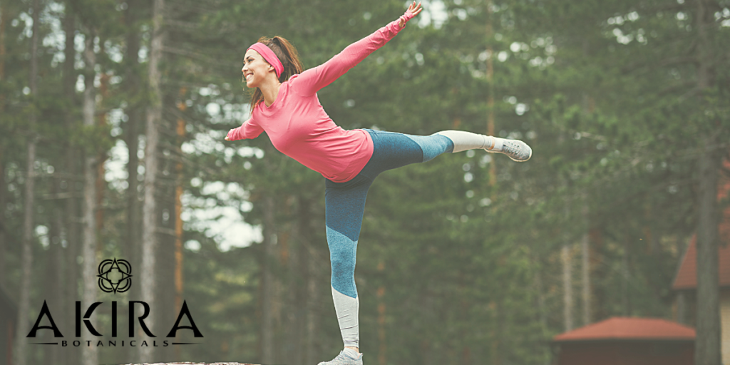 a woman outside balancing on one leg wearing a red long sleeve top and matching headband with leggings.
