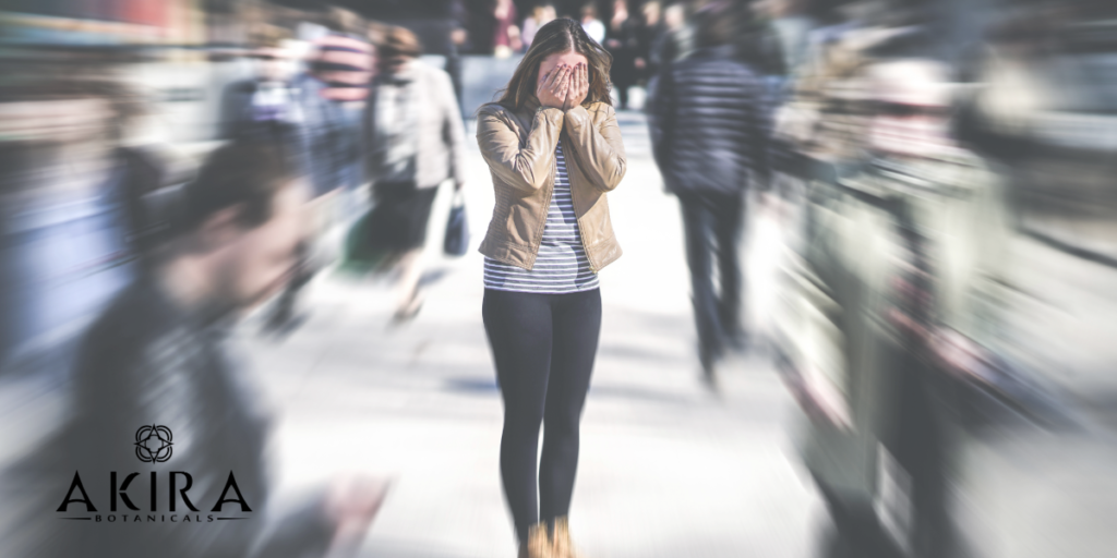 A woman in the middle of the street covering her face with anxiousness. The content around her is blurred.